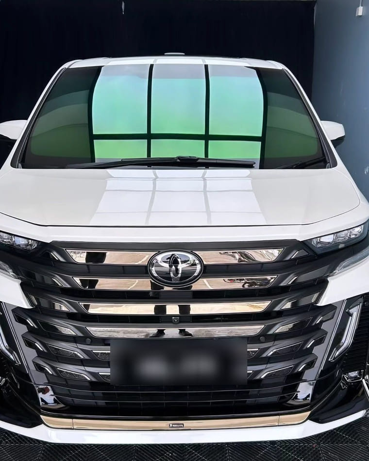 A white Toyota Vellfire finished in the bay, front grille and bonnet catching the overhead panel.